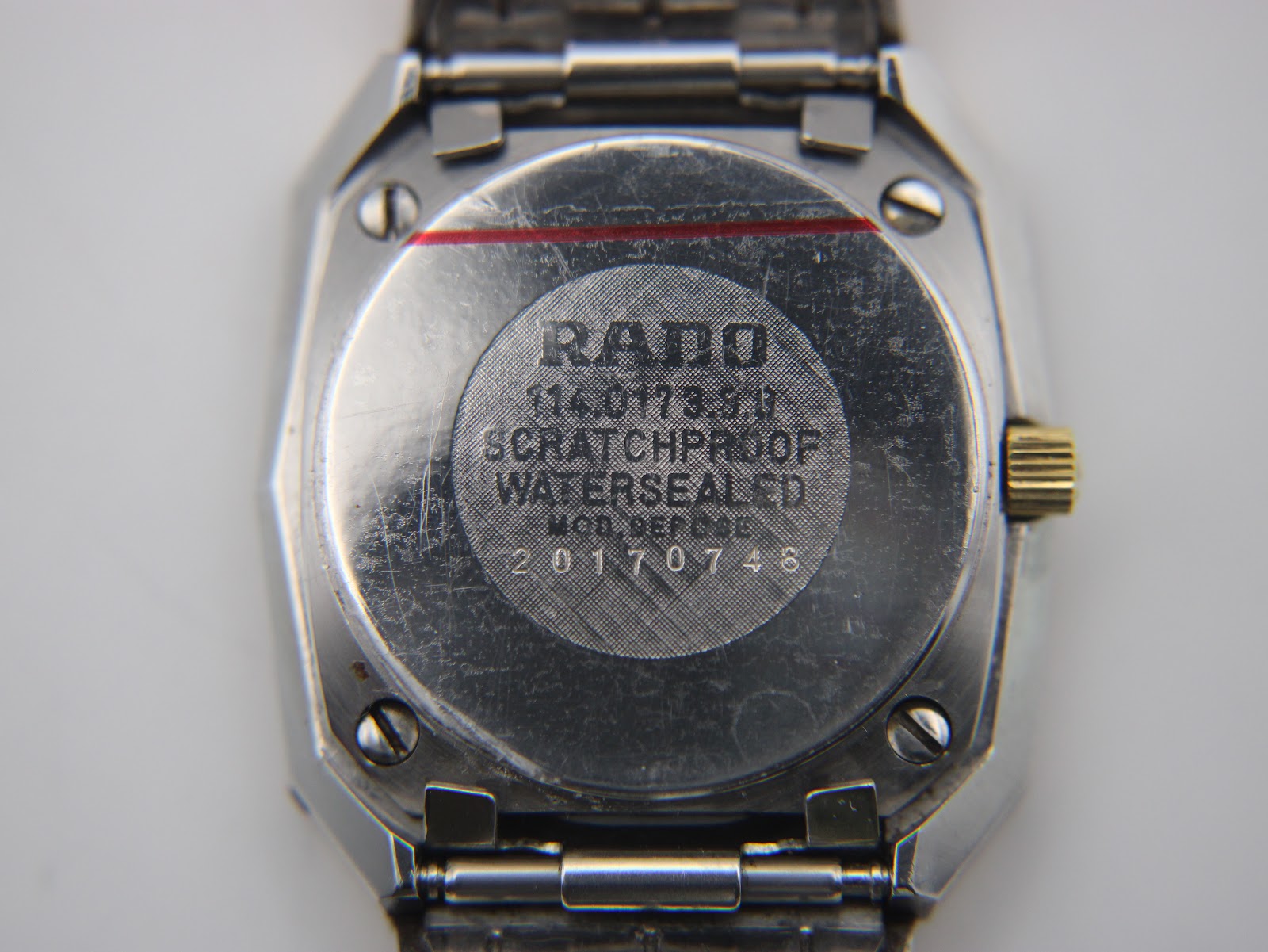 Interior of the removed case back, showing 'Rado Watch Co Swiss Stainless Steel'.