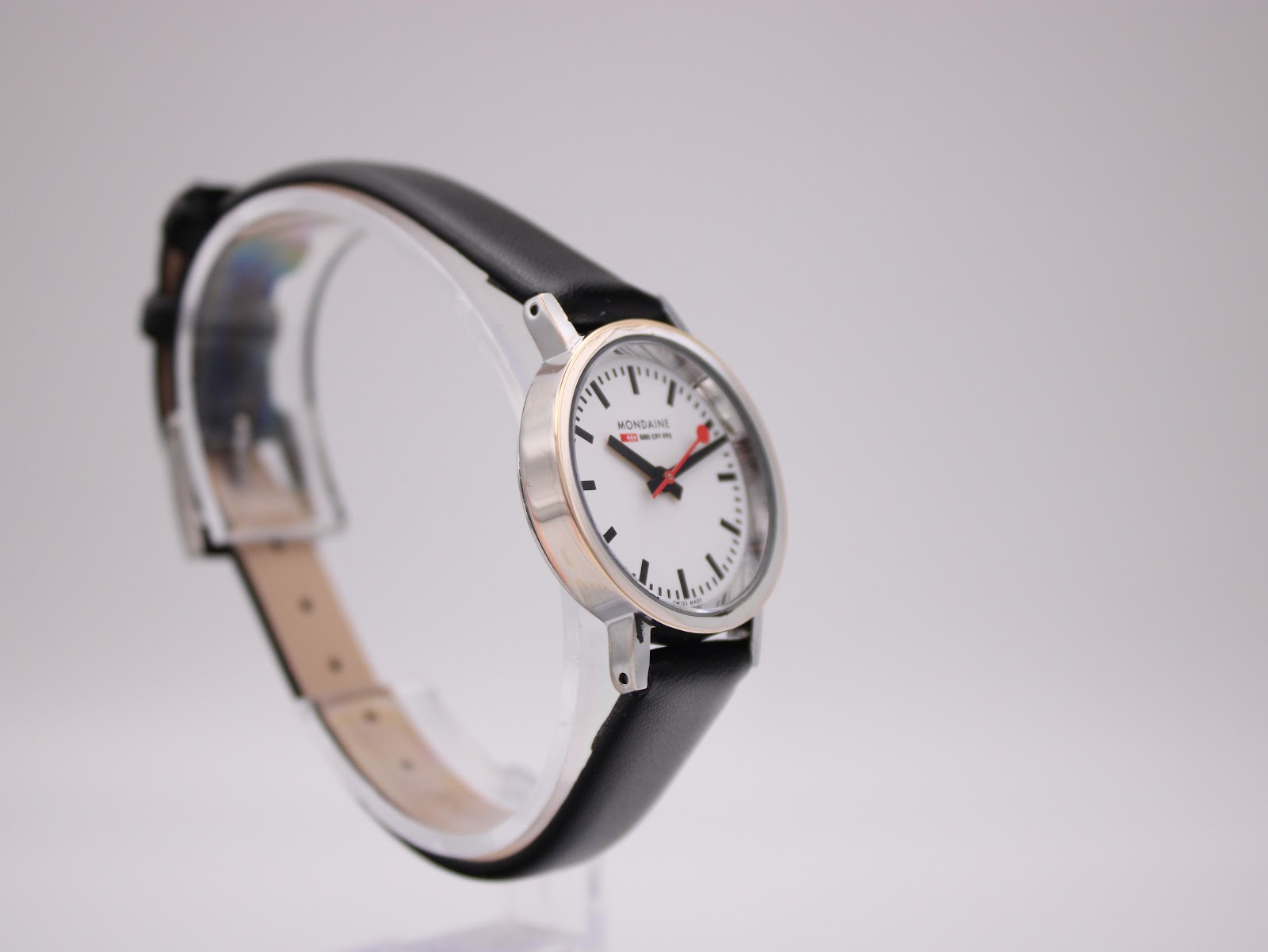 Another angled side view of the Mondaine 3831 watch on a stand, showcasing the sleek profile.