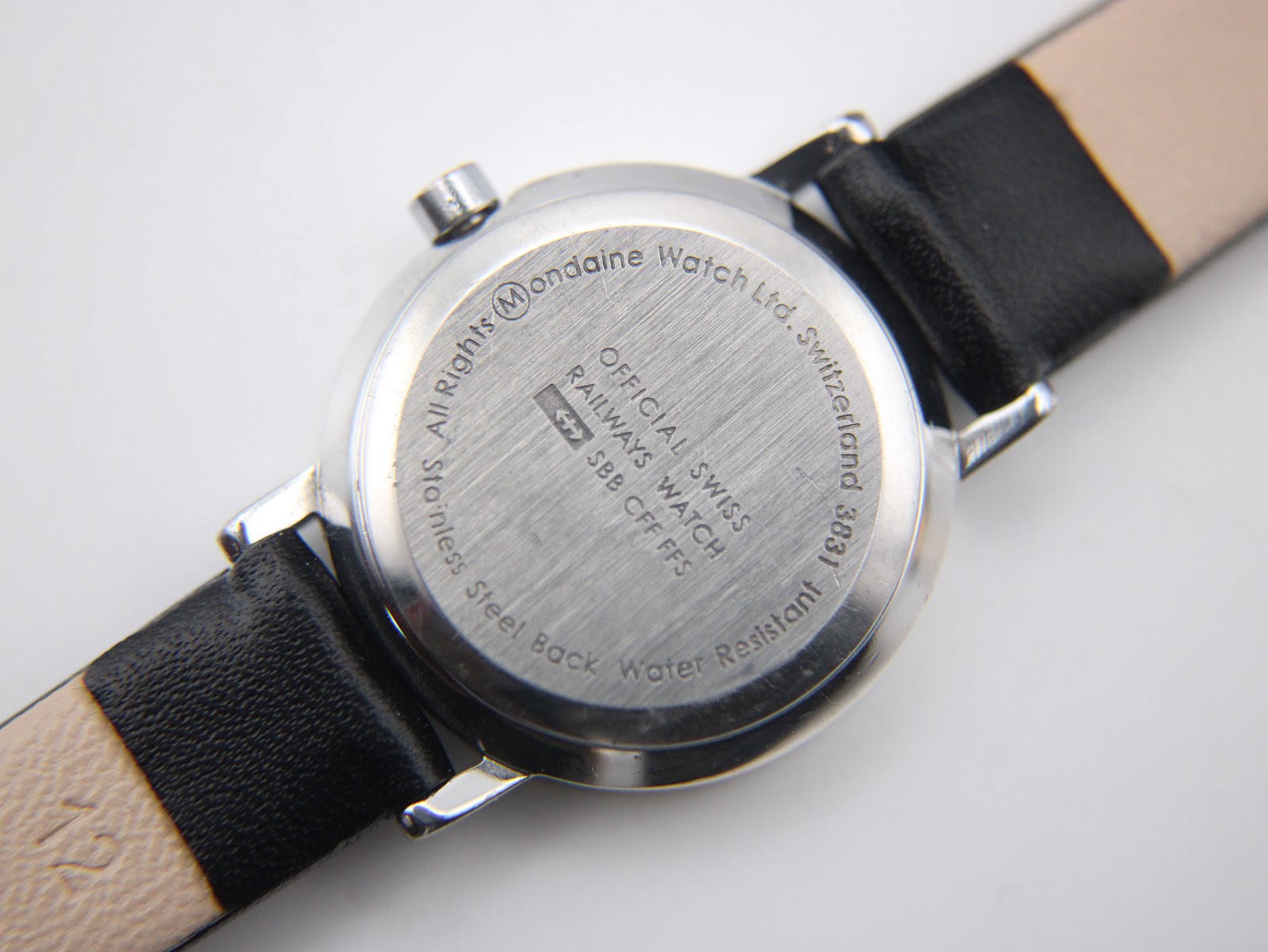 Close-up of the watch case back, detailing 'Mondaine Watch Ltd. Switzerland', 'Official Swiss Railways Watch', '3831', and 'Water Resistant' engravings.