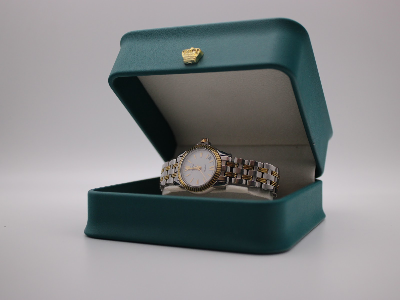 Tissot Ballade watch presented in its original dark green presentation box, adorned with a distinctive gold crown emblem.