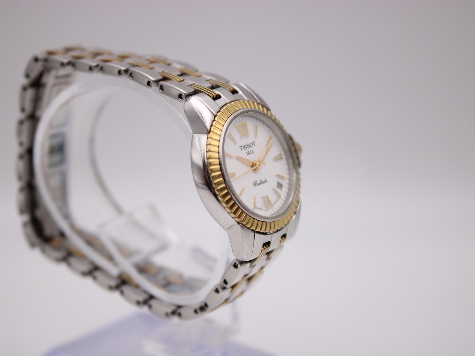 Another angled side view of the Tissot Ballade on a display stand, highlighting the integrated two-tone bracelet design.