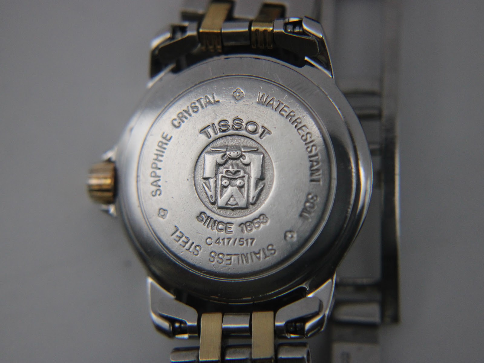 Close-up of the Tissot Ballade stainless steel case back, showing engravings for 'SAPPHIRE CRYSTAL', 'WATERRESISTANT', 'STAINLESS STEEL', 'SINCE 1853', and serial C 417/517.