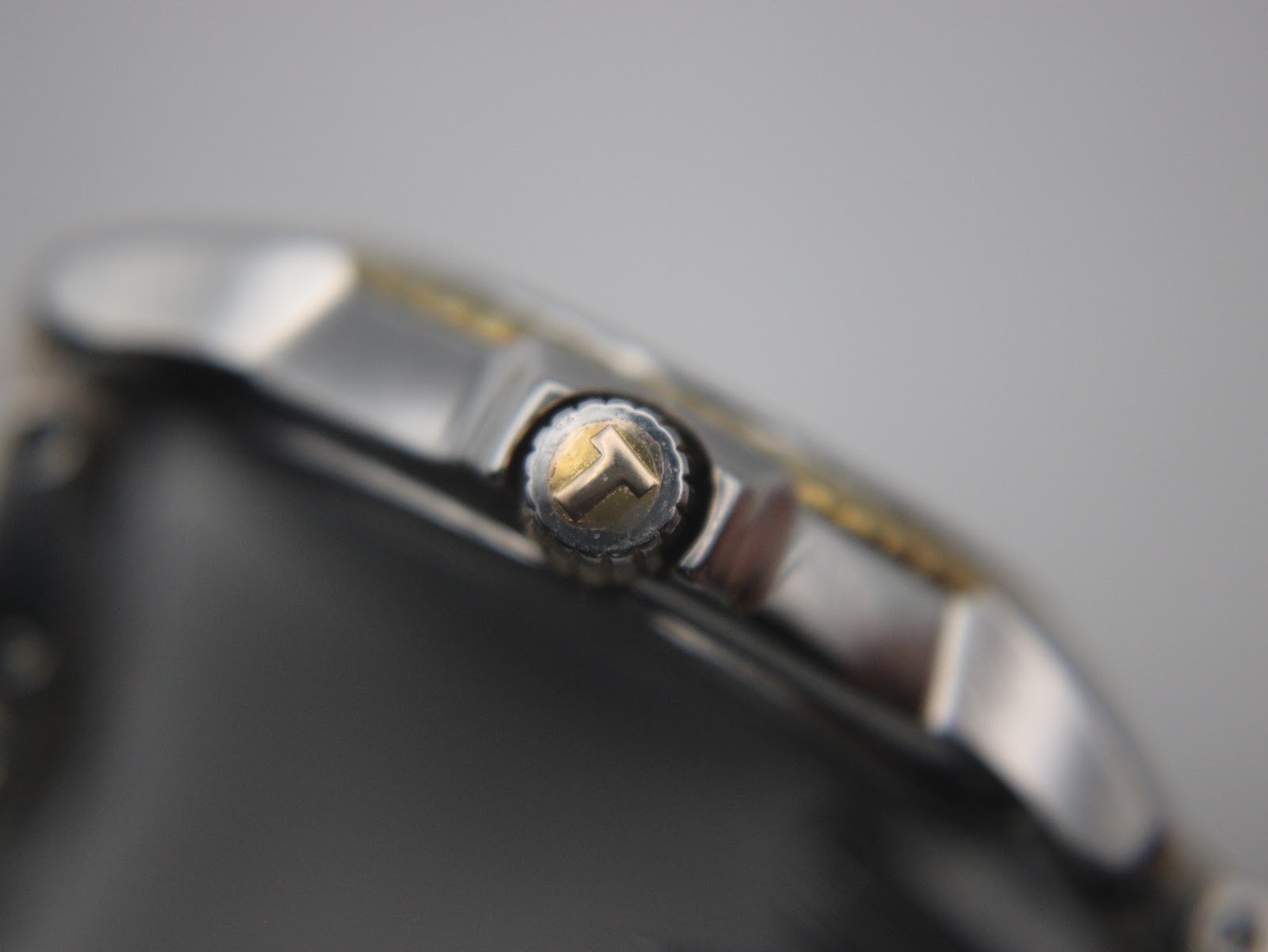 Close-up side view of the gold PVD crown, clearly showing the embossed Tissot 'T' logo.