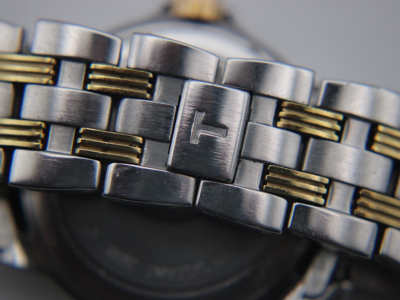 Close-up of the integrated two-tone steel bracelet, with a brushed finish and a hidden butterfly clasp featuring a Tissot 'T' logo.