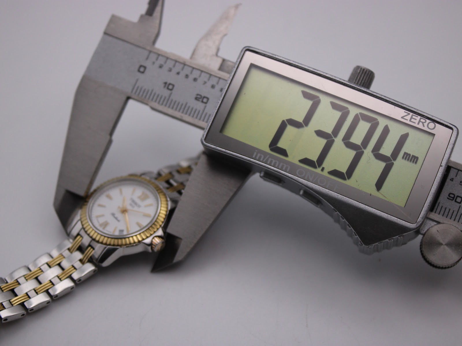 Digital caliper measuring the case diameter of the Tissot Ballade watch, displaying a precise measurement of 23.94mm.