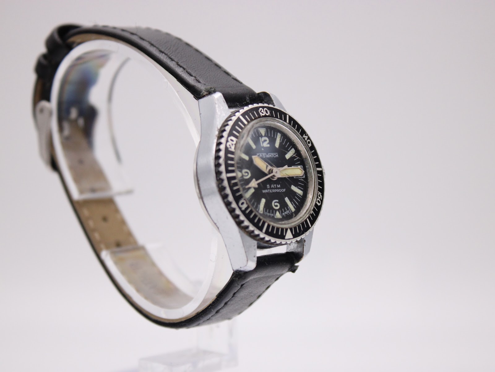 Another angled side view of the CASWATCH watch, showing the case profile and black leather strap.