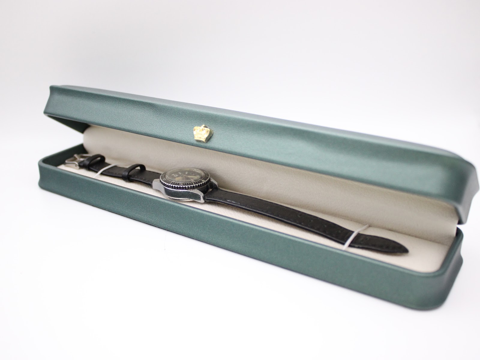 The CASWATCH watch nested inside its original long, green presentation box with cream interior.