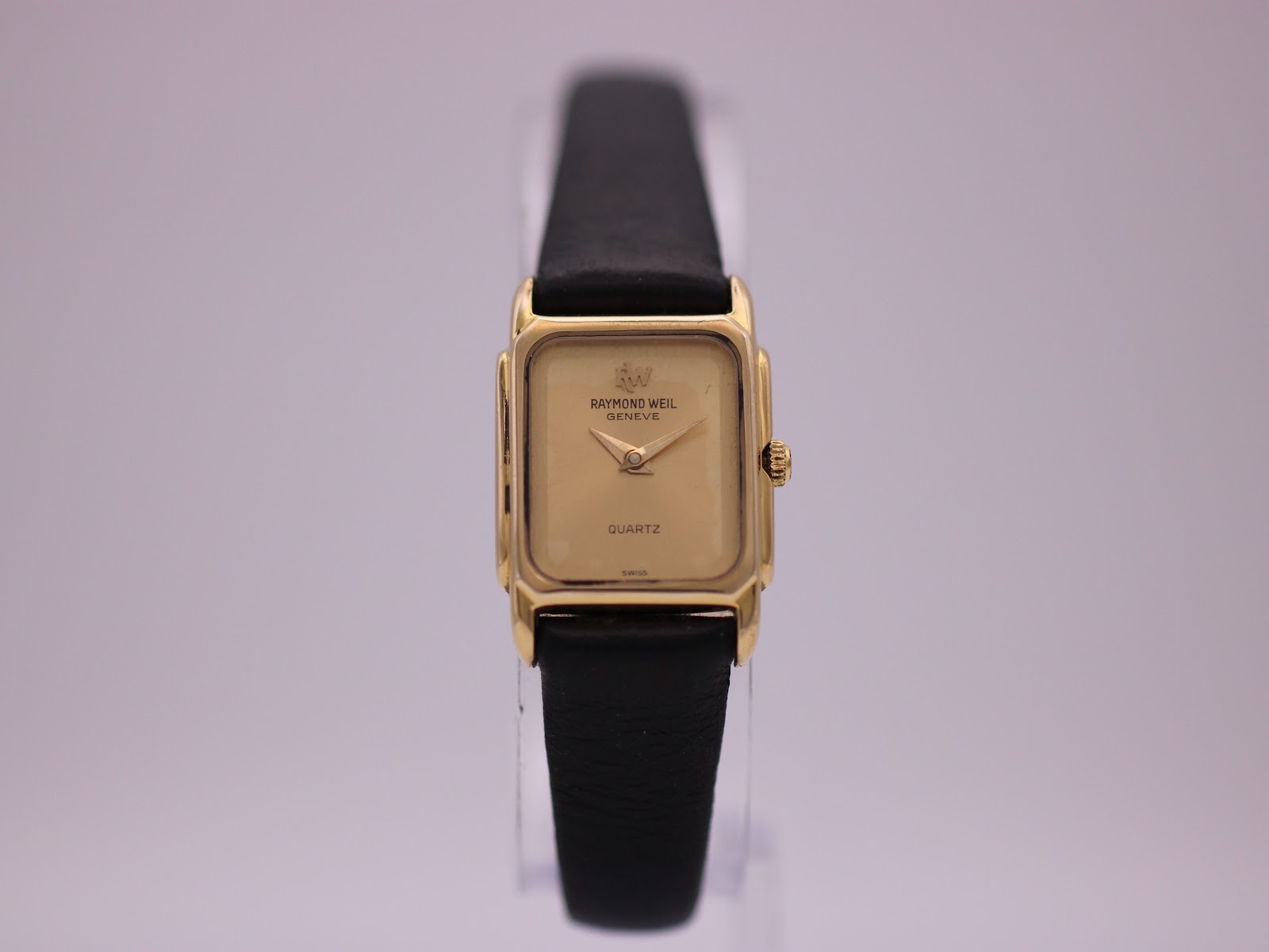 Front view of the Raymond Weil 5700 ladies watch, showing its rectangular gold electroplated case and champagne dial with a black leather strap.