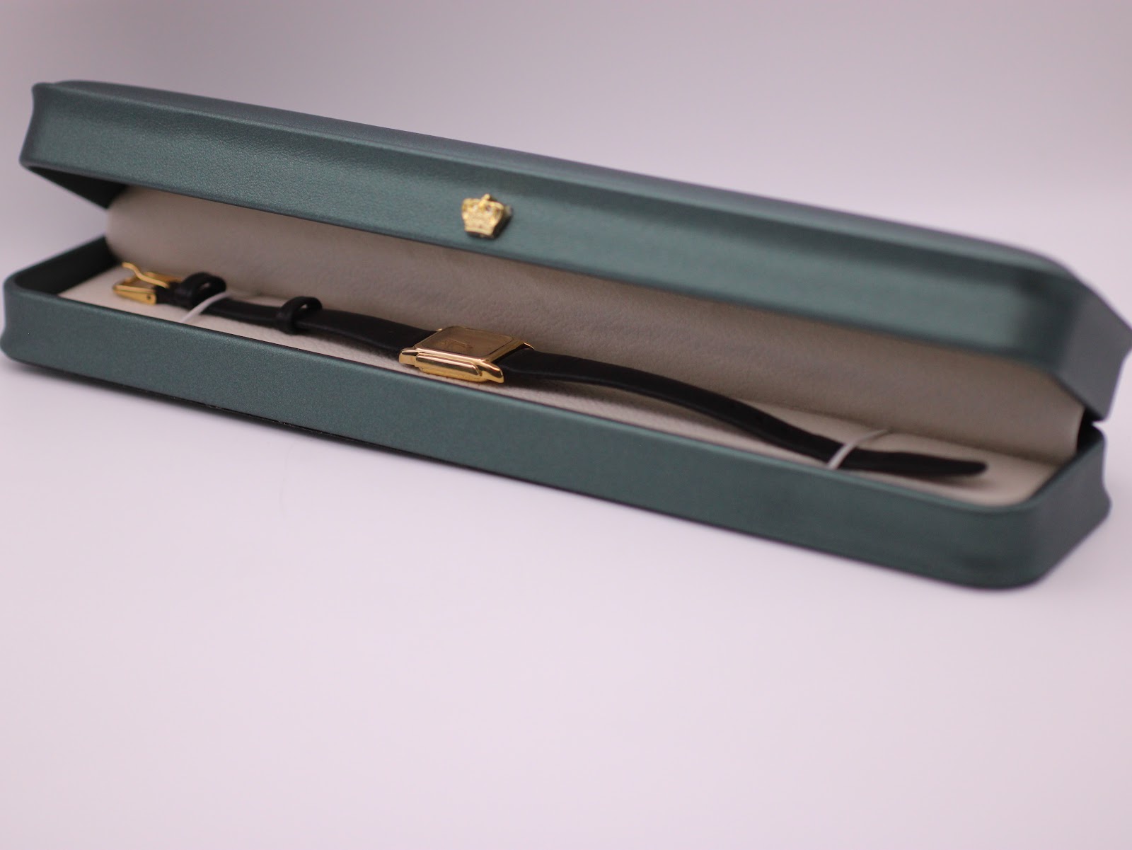 The Raymond Weil watch resting inside its original dark green presentation box with a cream interior.