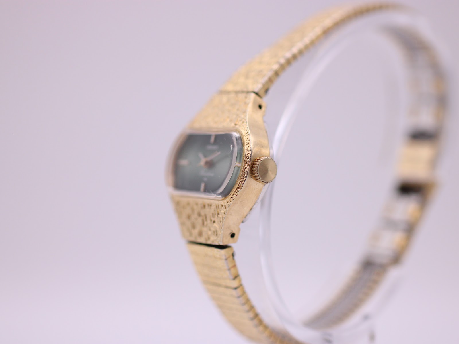 Angled side view of the Seiko Rainbow watch, showing the textured gold-tone case, integrated bracelet, and crown.