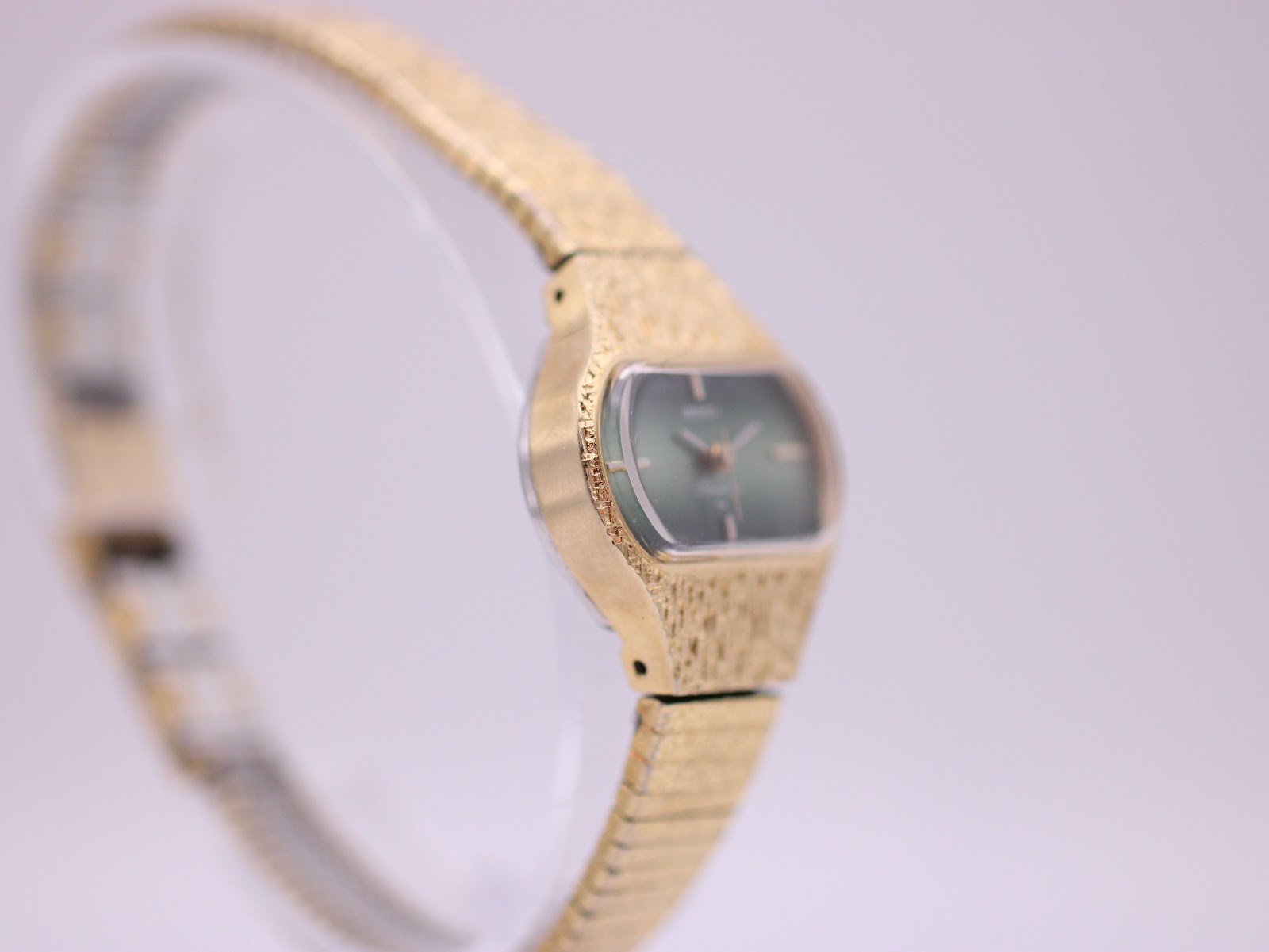 Opposite angled side view of the Seiko Rainbow watch, highlighting the unique textured gold-tone case design and integrated bracelet.