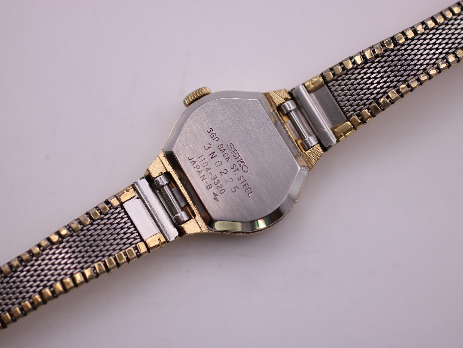 Close-up of the Seiko watch case back showing engraved text: 'SEIKO SGP BACK ST STEEL 3N0225 1104-3320 JAPAN-B'.