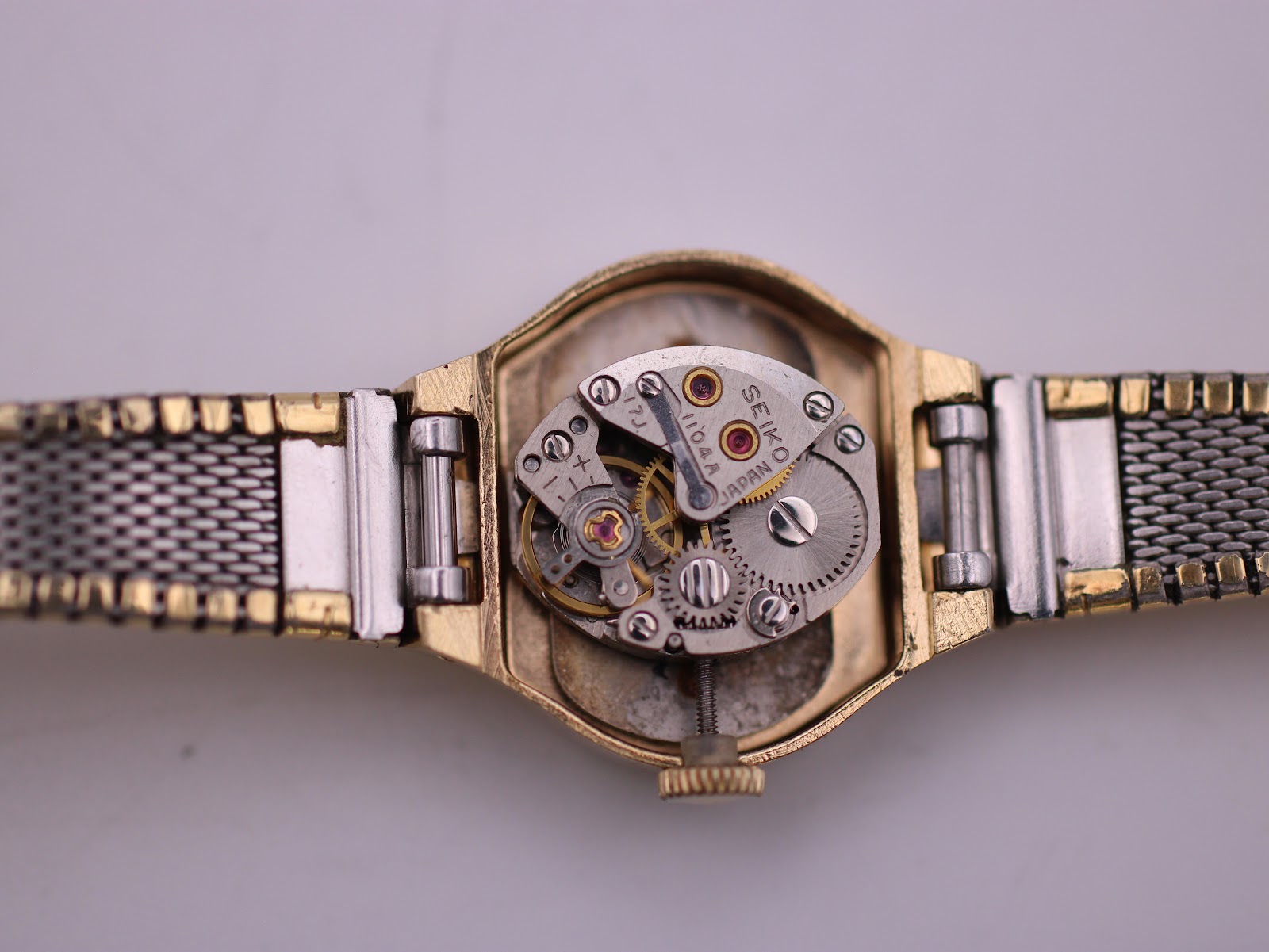 Close-up of the open watch case revealing the intricate Seiko 1104A manual wind movement with visible gears and jewels.
