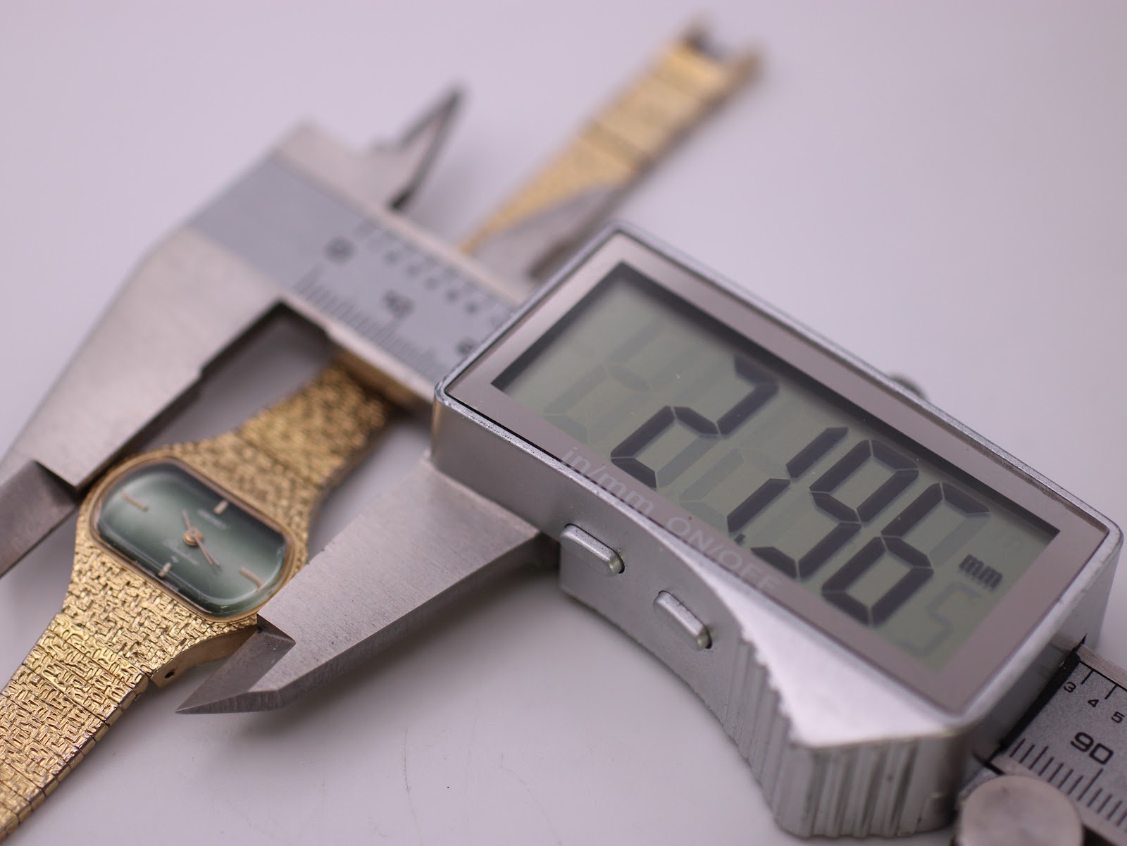 Digital caliper measuring the case width of the Seiko Rainbow watch, displaying a precise measurement of 21.96 mm.