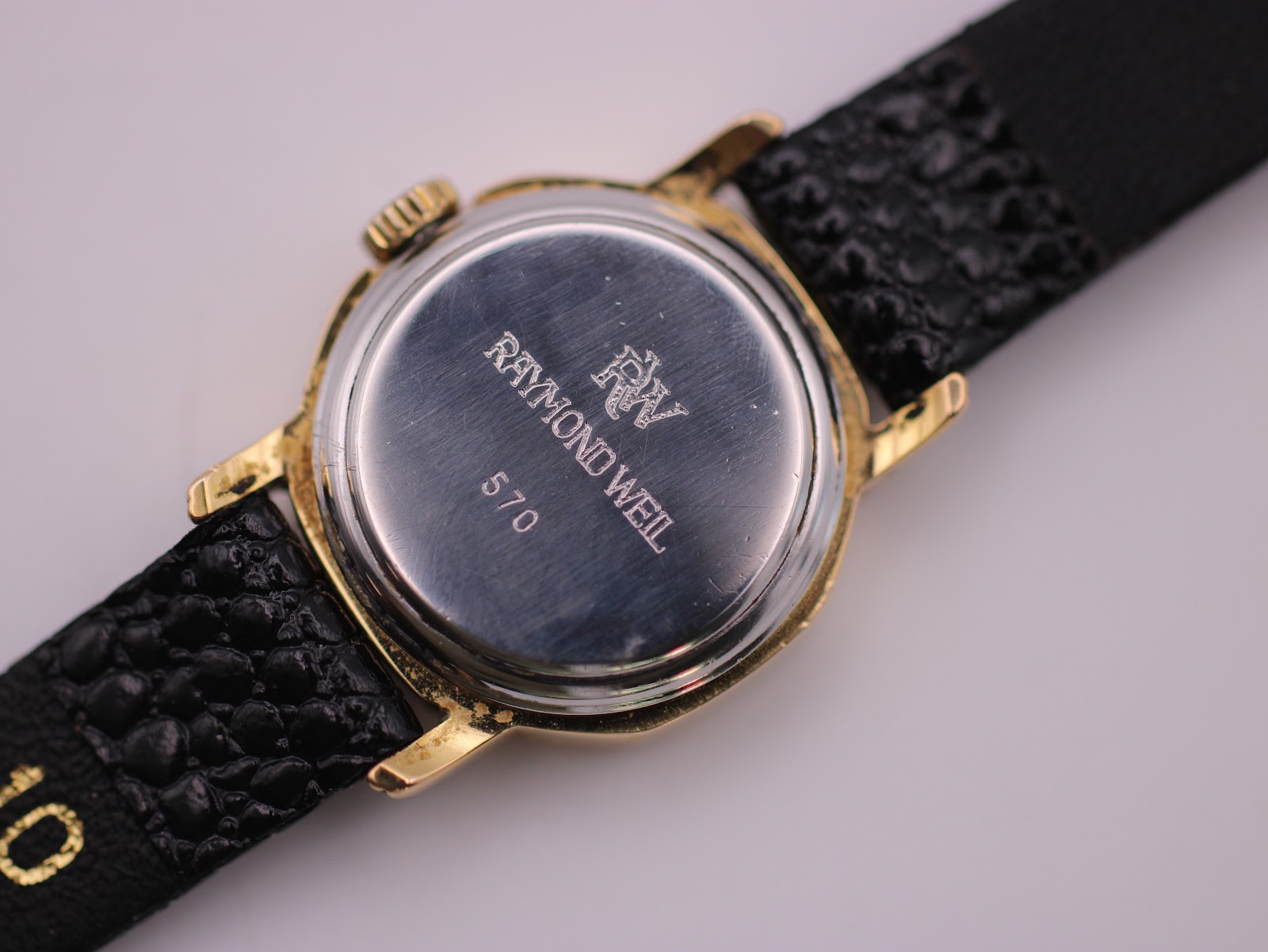 Close-up of the stainless steel case back, engraved with "RAYMOND WEIL GENEVE" and model number "570".