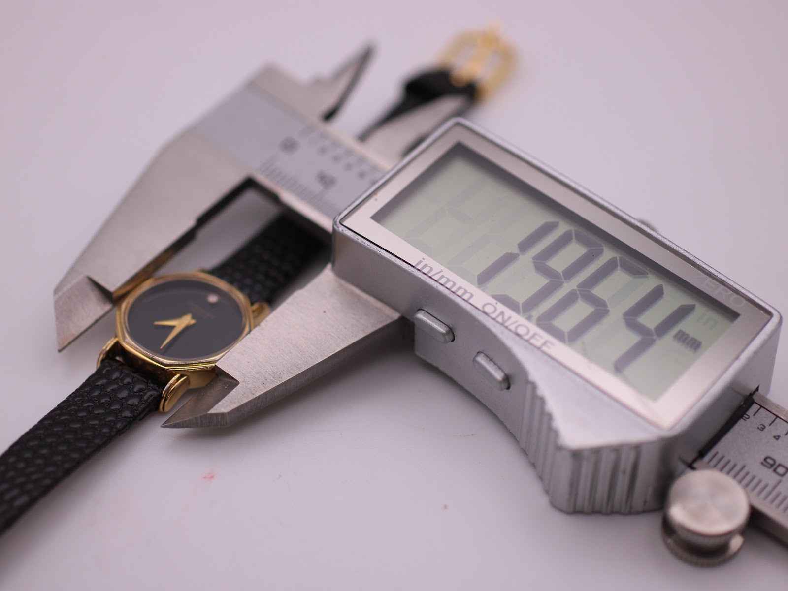 Digital caliper measuring the Raymond Weil watch case, displaying a precise diameter of 19.64mm.