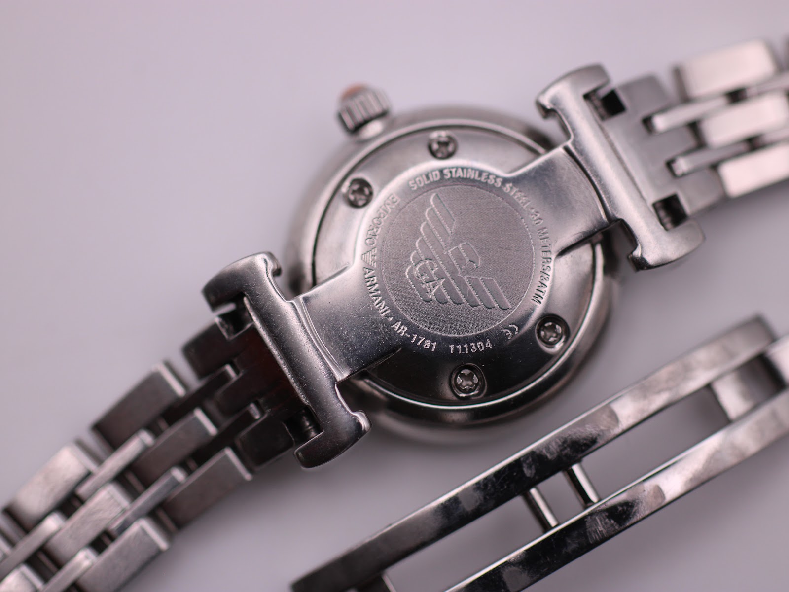 Detailed view of the Emporio Armani AR-1781's solid stainless steel case back with model (AR-1781) and serial (111304) engravings, showing the integrated bracelet and butterfly clasp.