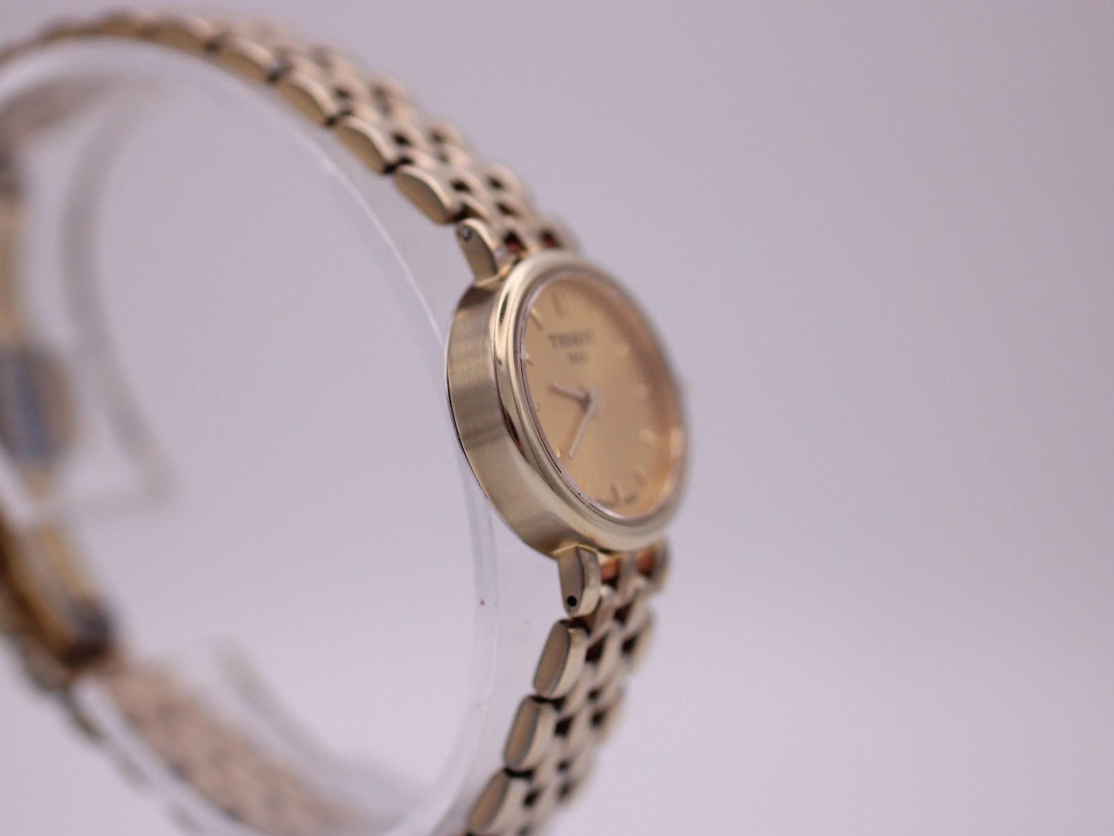 Opposite angled side view of the Tissot watch, highlighting the polished gold-tone case and bracelet links.