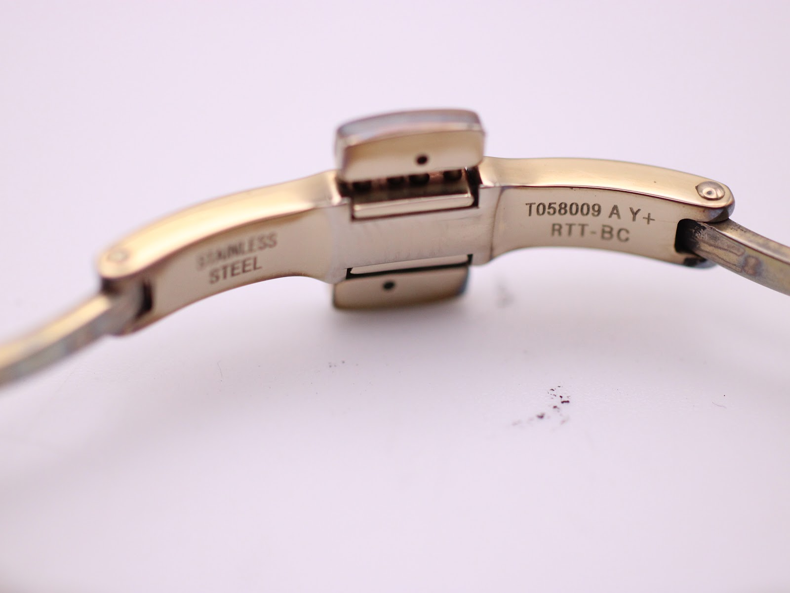 Close-up of the watch's folding clasp interior, showing 'STAINLESS STEEL' and the model reference 'T058009'.