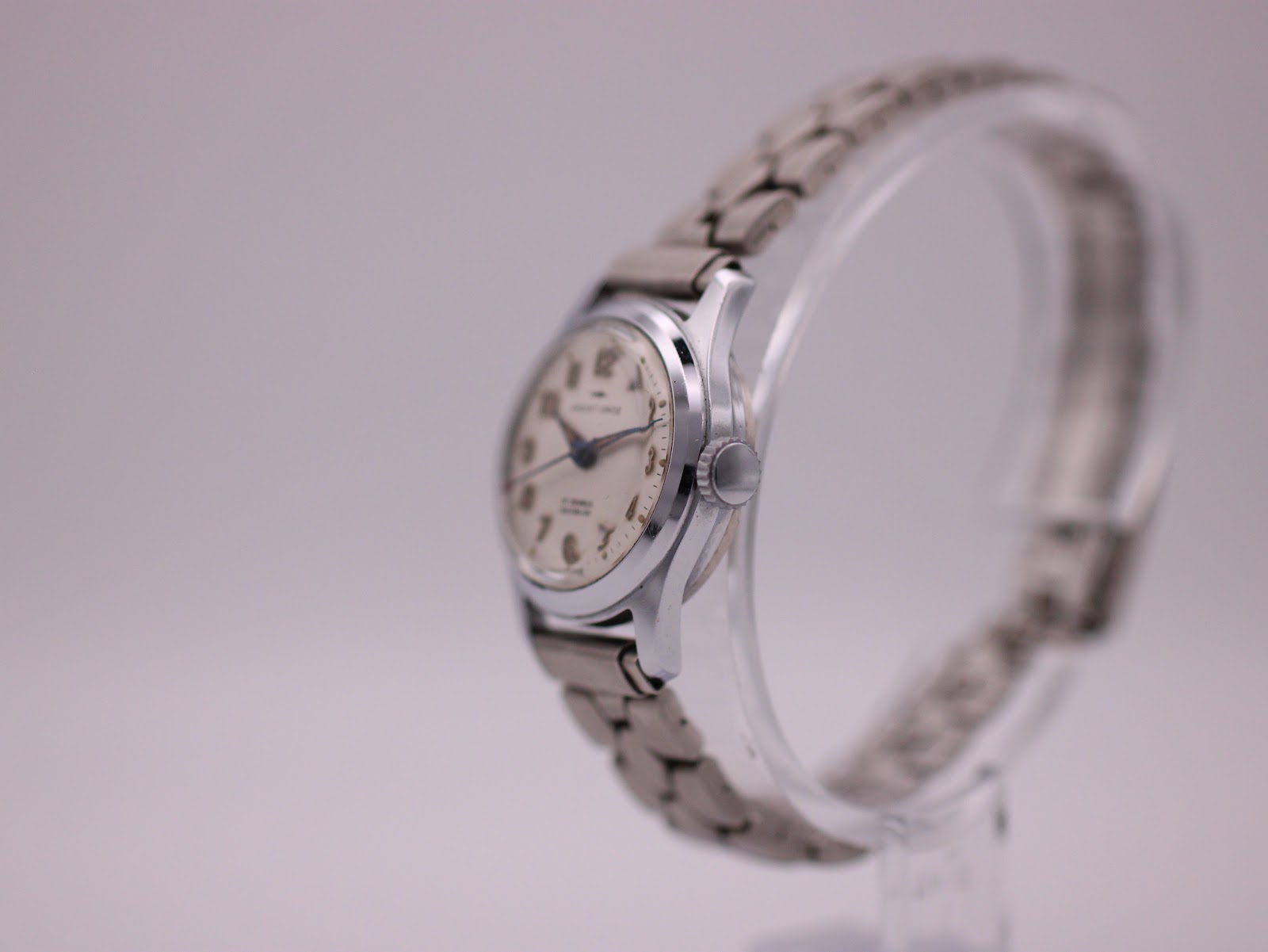 Side view of the Jaquet-Droz watch showing the crown and case profile on a display stand.