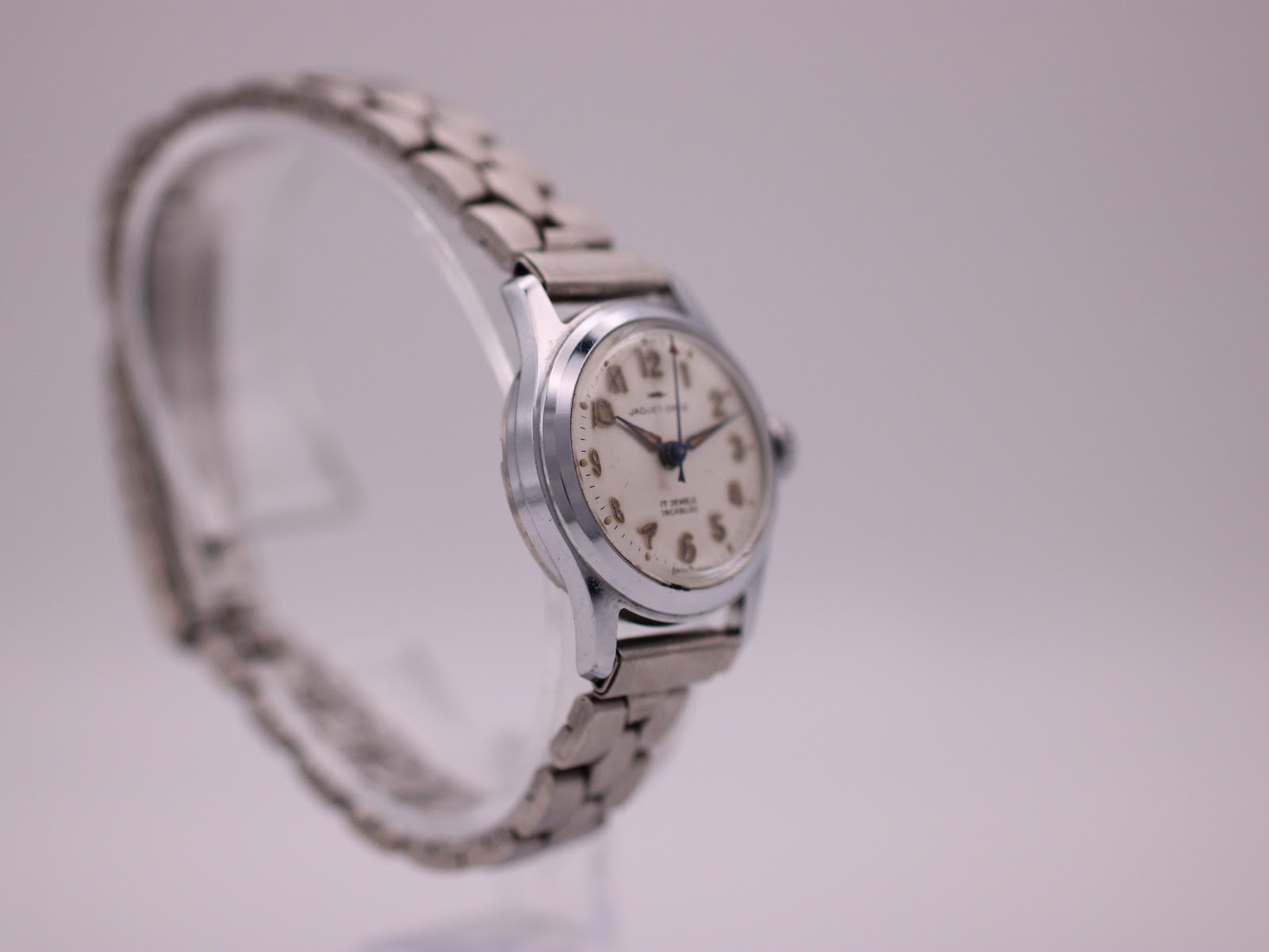 Angled side view of the Jaquet-Droz watch highlighting the dial and bracelet on a display stand.