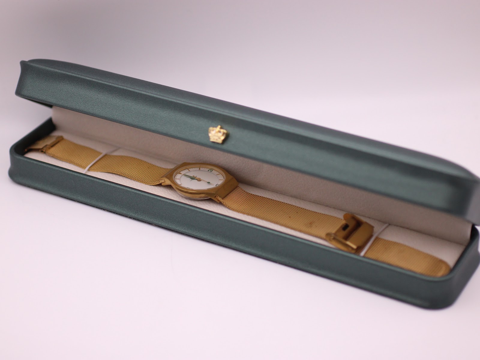 The gold-tone Toy Watch displayed inside its original dark green presentation box.