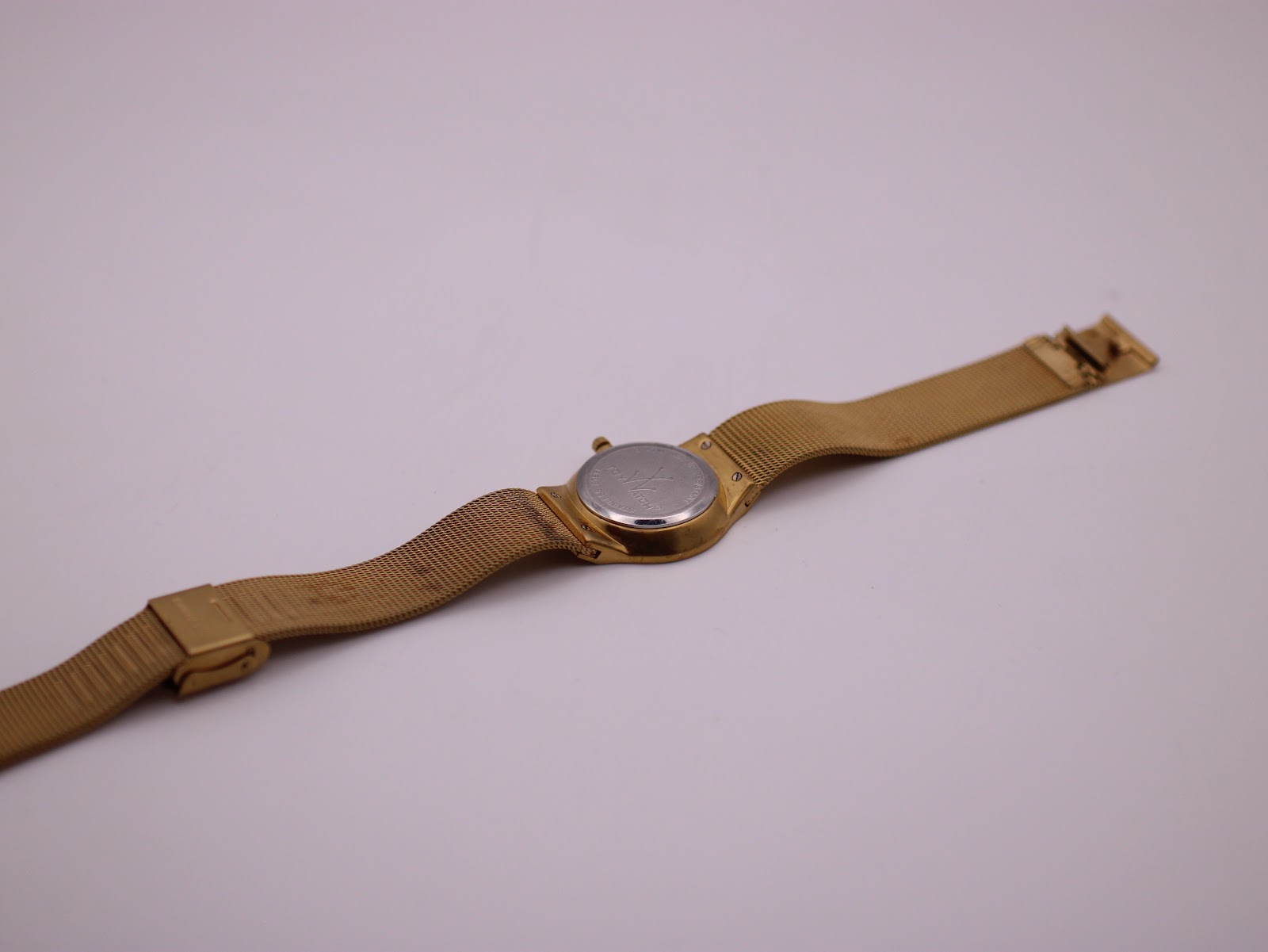 Back view of the full gold-tone Toy Watch laid flat, revealing the stainless steel case back.