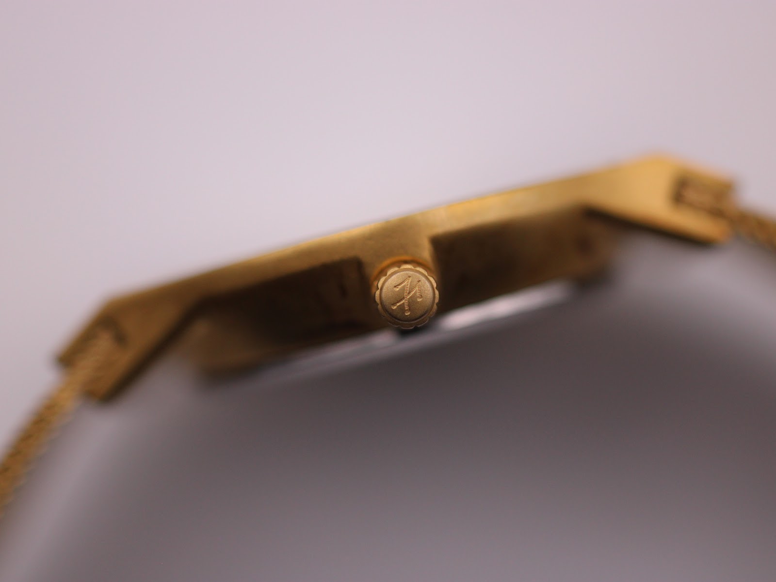 Close-up of the signed crown on the side of the gold-tone Toy Watch case.