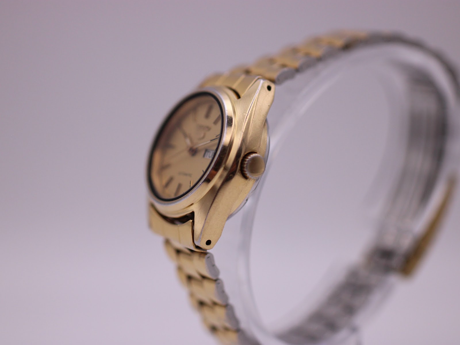 Side view of the gold-tone Seiko 5 watch, showing the crown and tonneau case shape.