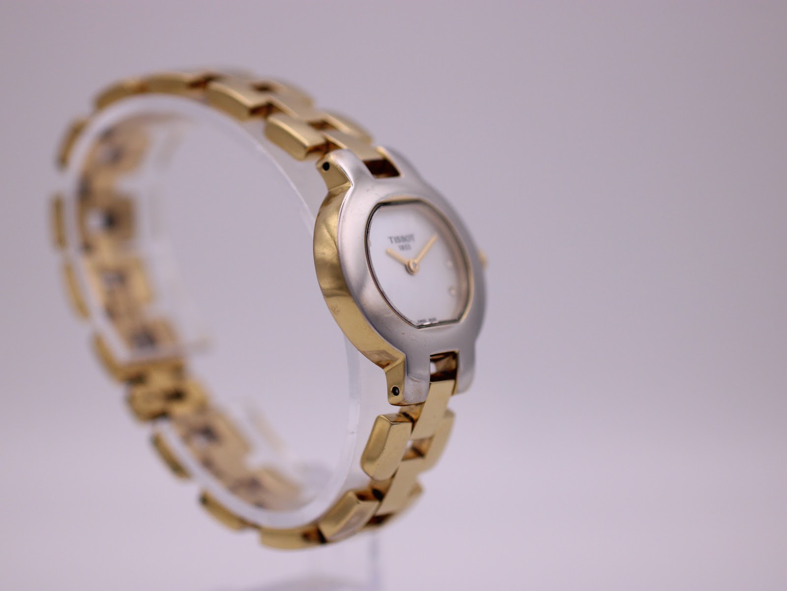 Another angled side view of the Tissot G330 watch on a stand, highlighting the design of the case and bracelet.