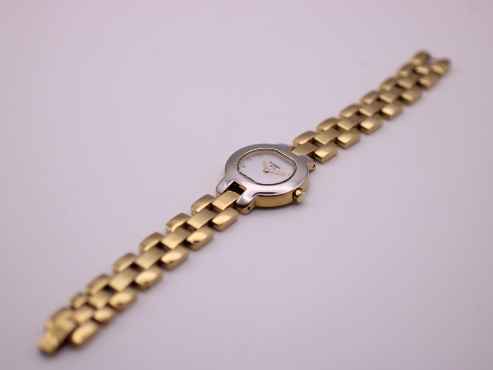 Overhead view of the entire Tissot G330 watch and bracelet laid flat, showing its full length.