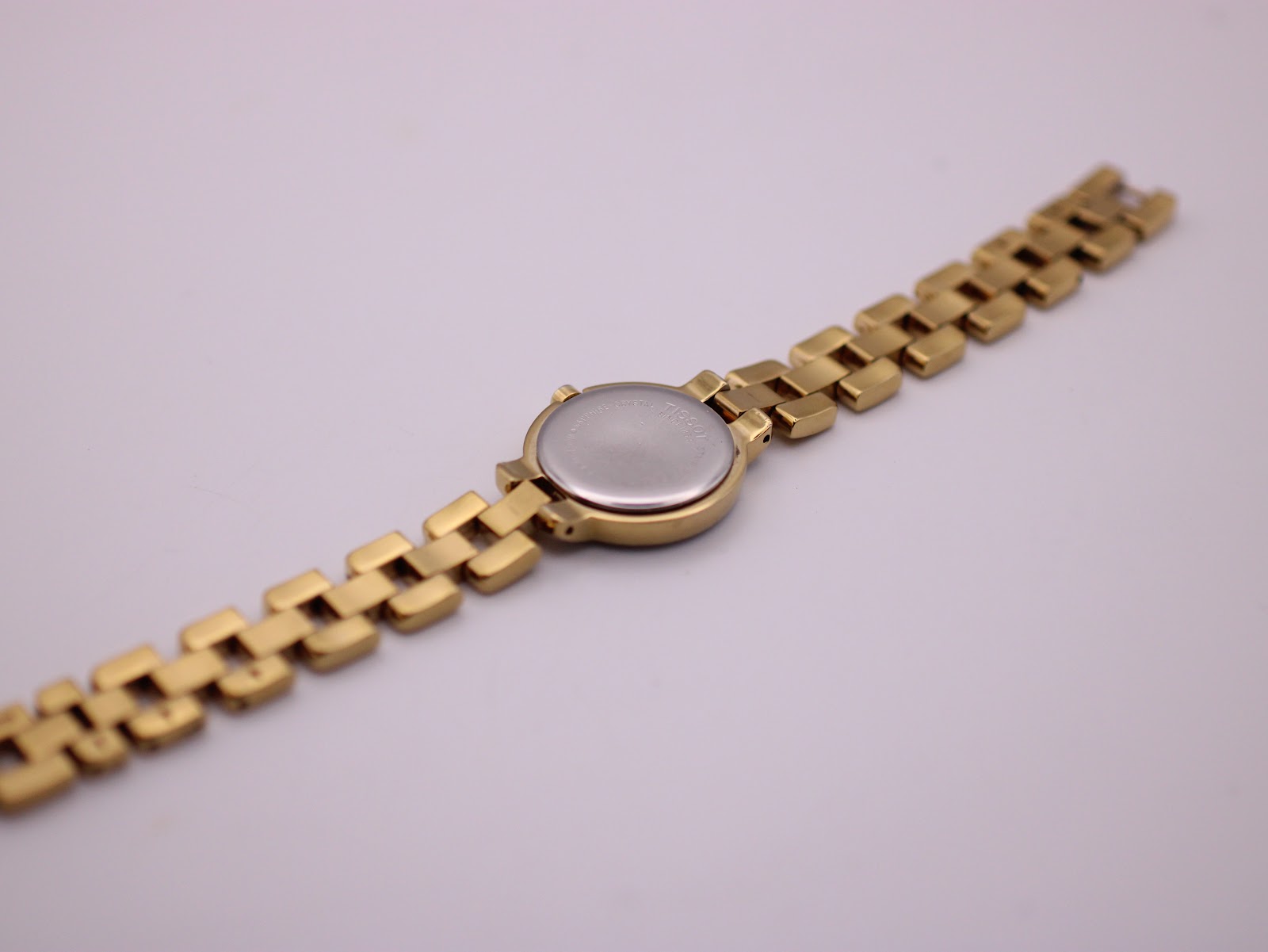 Back view of the Tissot G330 watch and bracelet, showing the stainless steel case back and the integrated gold-tone links.