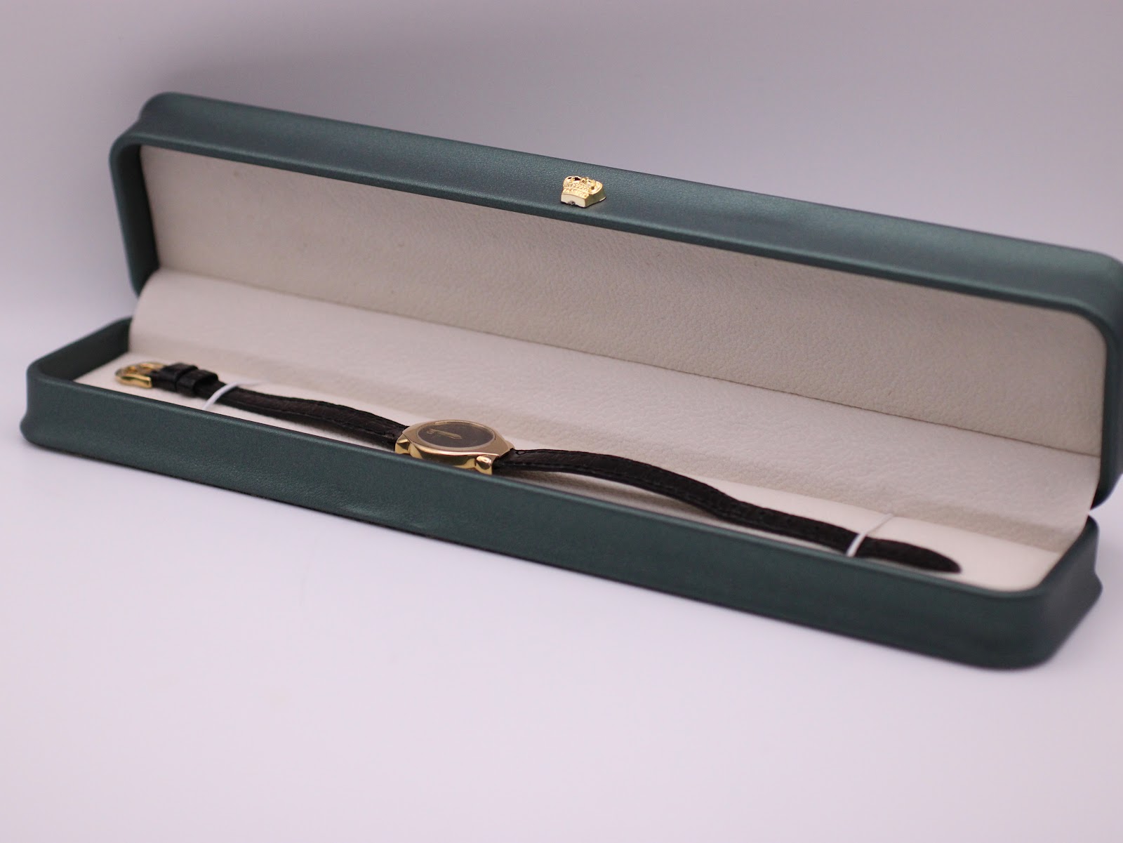 The Raymond Weil watch neatly placed inside its original dark green presentation box, with a cream-coloured interior.