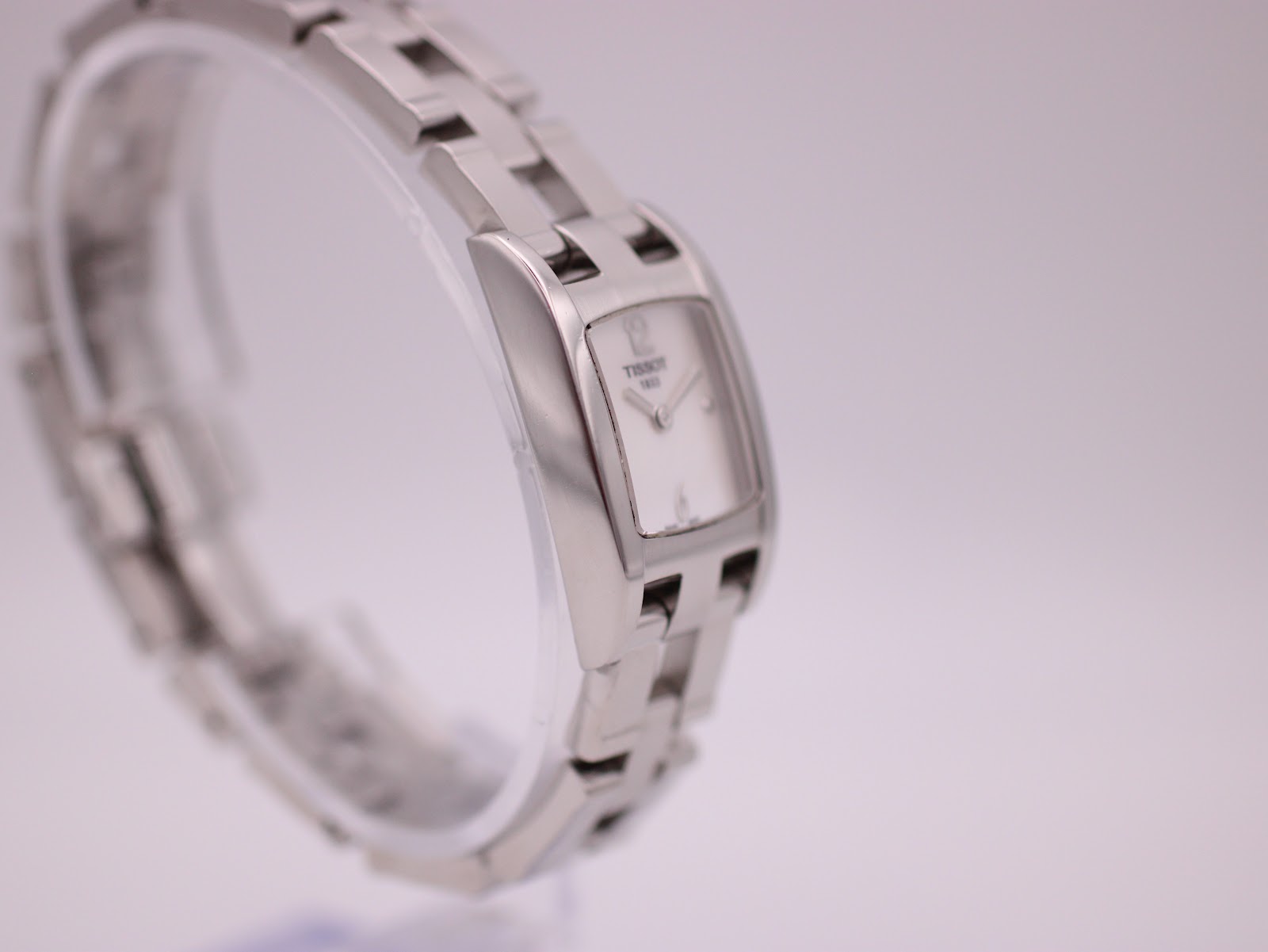 Another angled side view of the Tissot watch on a stand, highlighting the bracelet links.