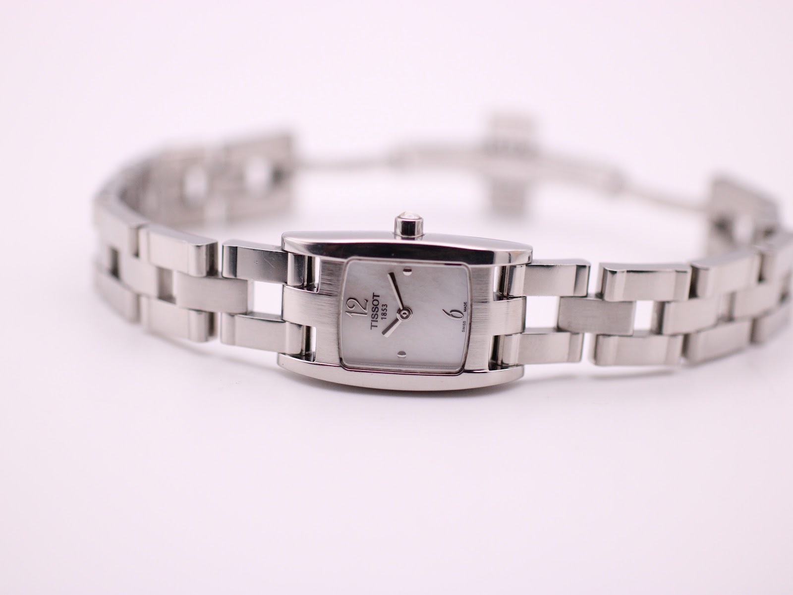 Front view of the Tissot watch laid flat, displaying the white dial and integrated steel bracelet.