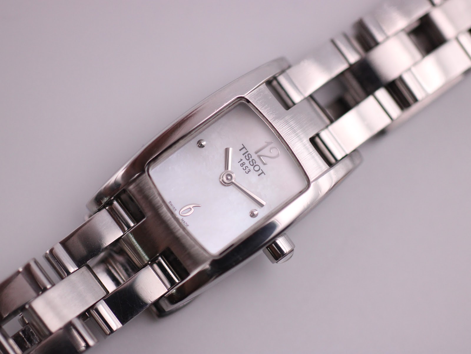 Close-up of the Tissot watch dial, showing 'TISSOT 1853', '12', '6' and 'swiss made' text.