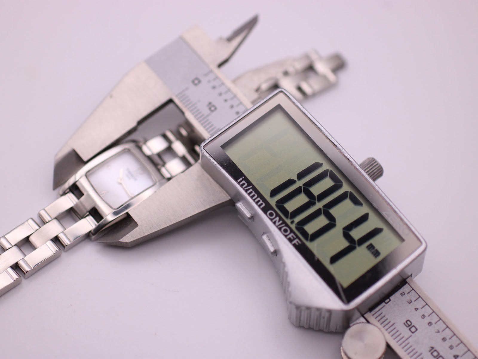 Digital caliper measuring the Tissot watch case, showing an exact reading of 18.64mm.