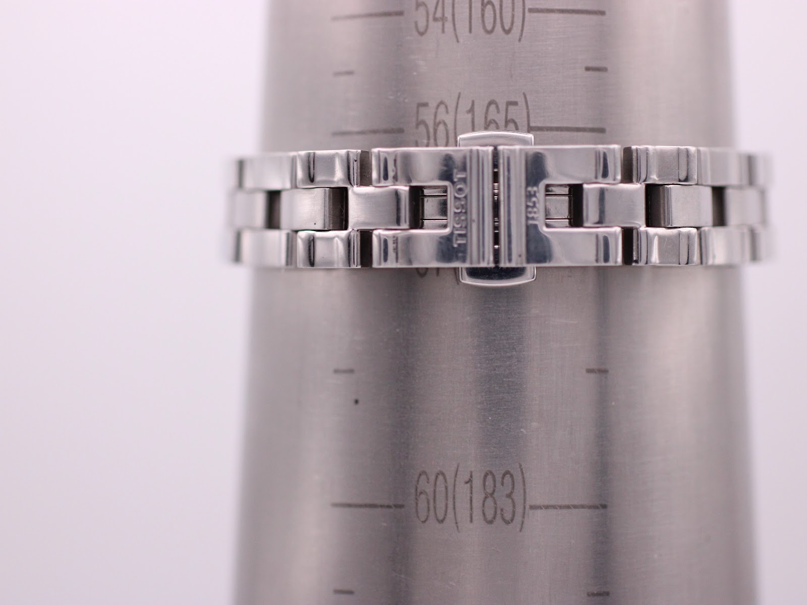 Close-up of the Tissot watch's integrated bracelet clasp on a wrist sizing gauge, indicating a wrist size of 160mm, with Tissot logo.