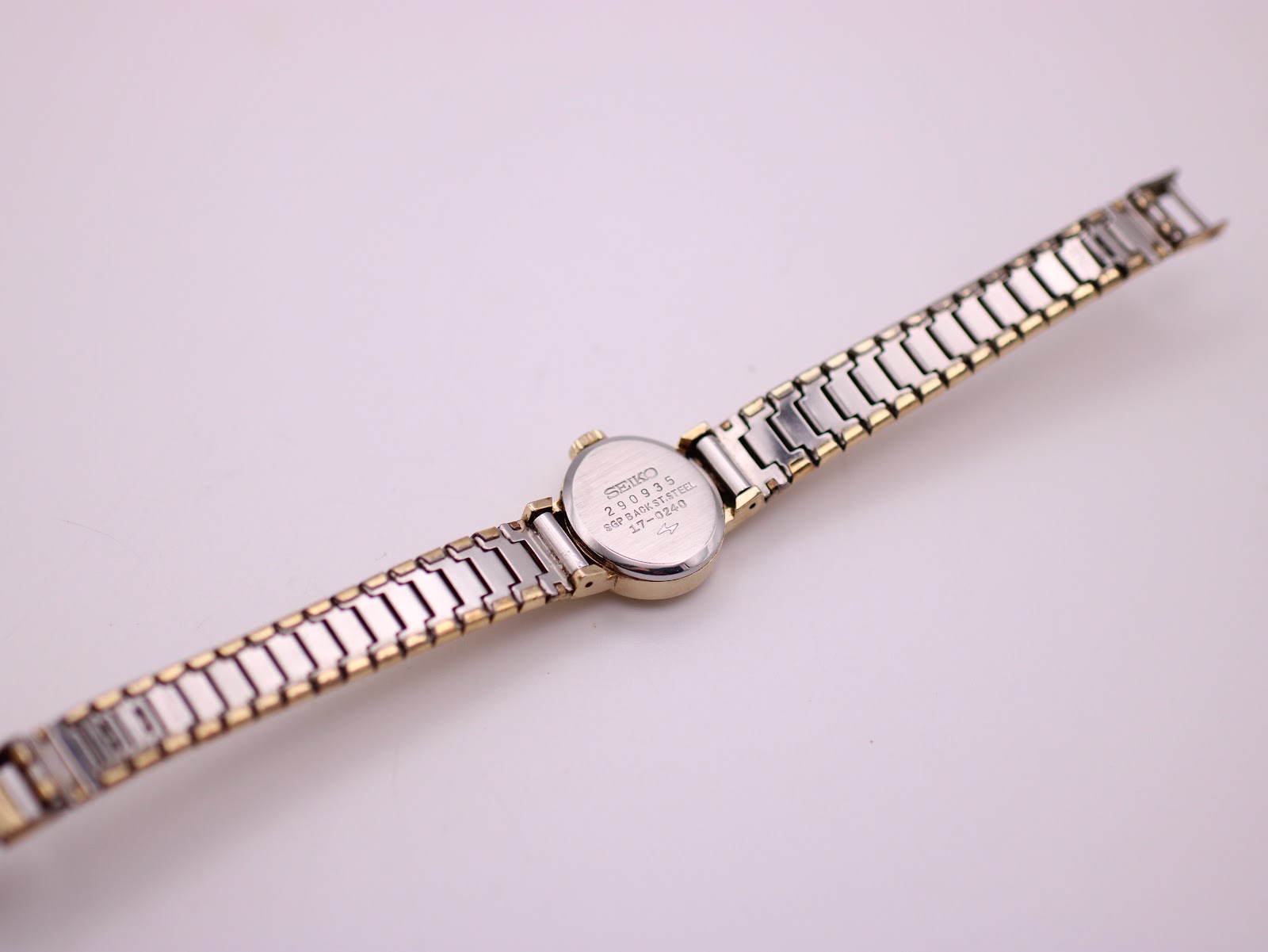 Back view of the Seiko watch, showing the stainless steel case back and the full length of the gold-coloured expanding bracelet.