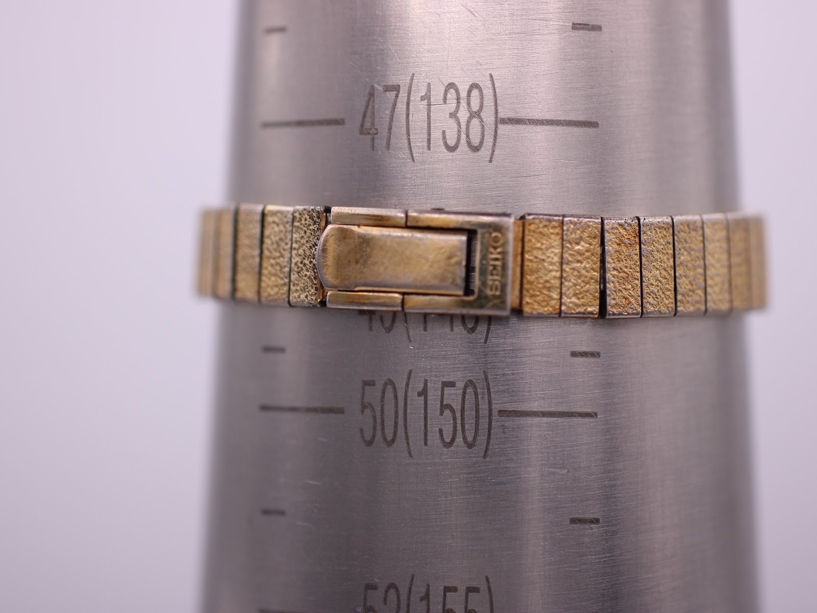 Close-up of the expanding bracelet clasp on a wrist sizing gauge, showing the signed "SEIKO" clasp and the approximate wrist circumference of 14.5cm.