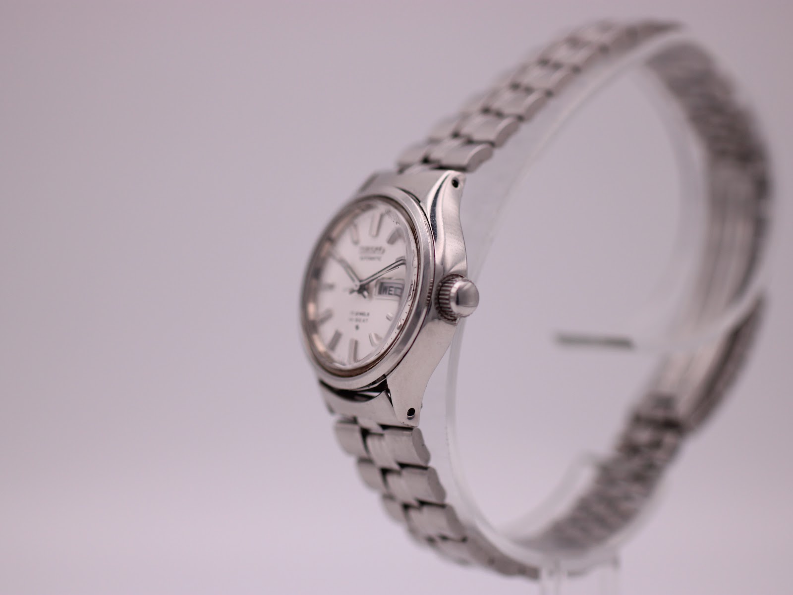 Right-side view of the vintage SEIKO watch, showing the crown and case profile on a clear stand.