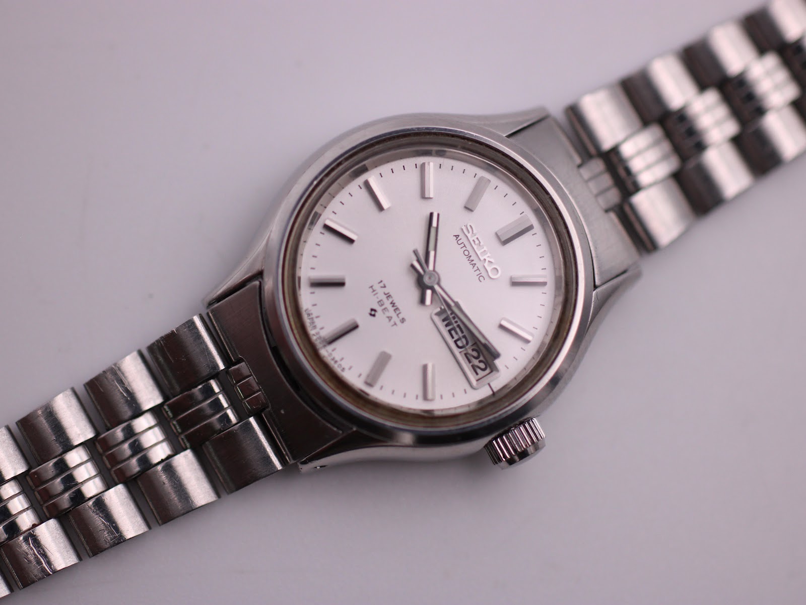 Close-up, slightly angled view of the SEIKO watch dial, showing the applied baton indices and the day-date window with 'WED 22'.