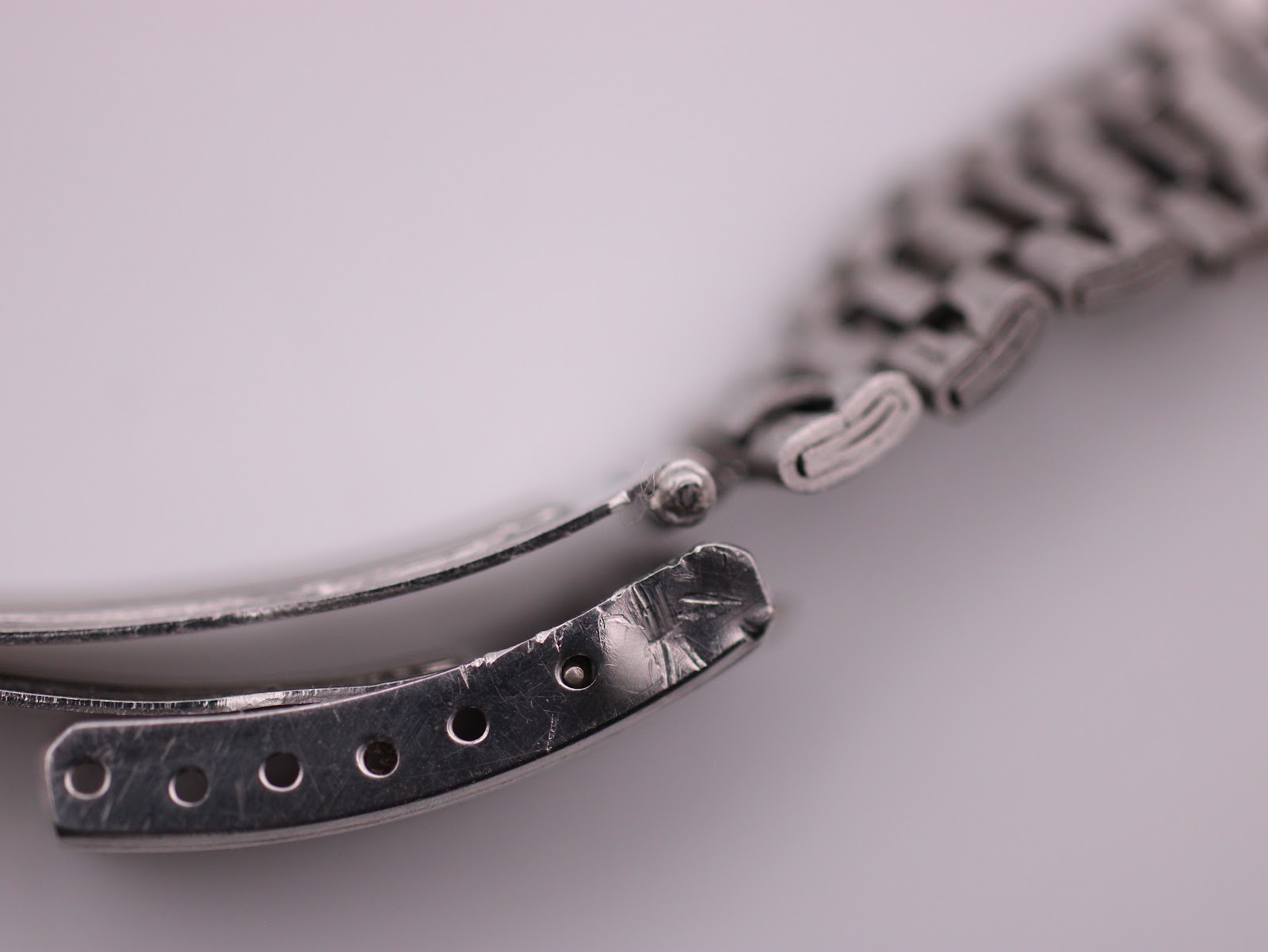 Close-up of the vintage SEIKO watch's folding clasp, showing adjustment holes and signs of wear.