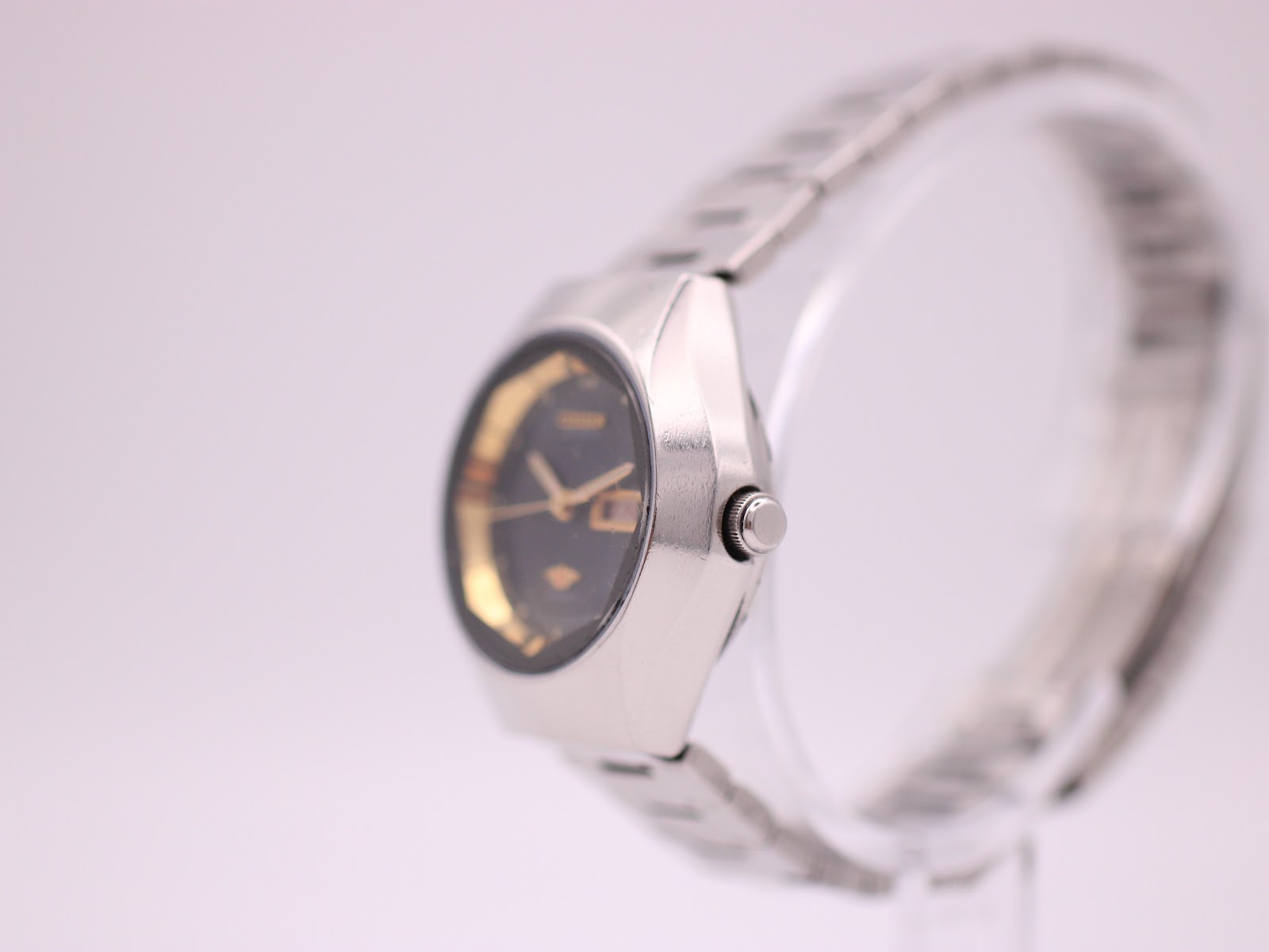 Right-side profile view of the Citizen watch, showing the octagonal case and crown, on a display stand.