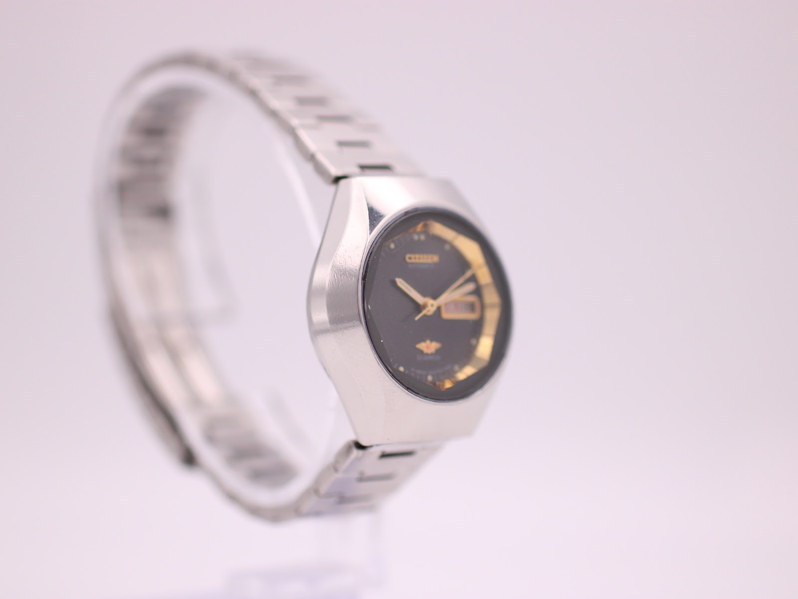 Left-side profile view of the Citizen watch, showing the integrated steel bracelet and case shape, on a display stand.