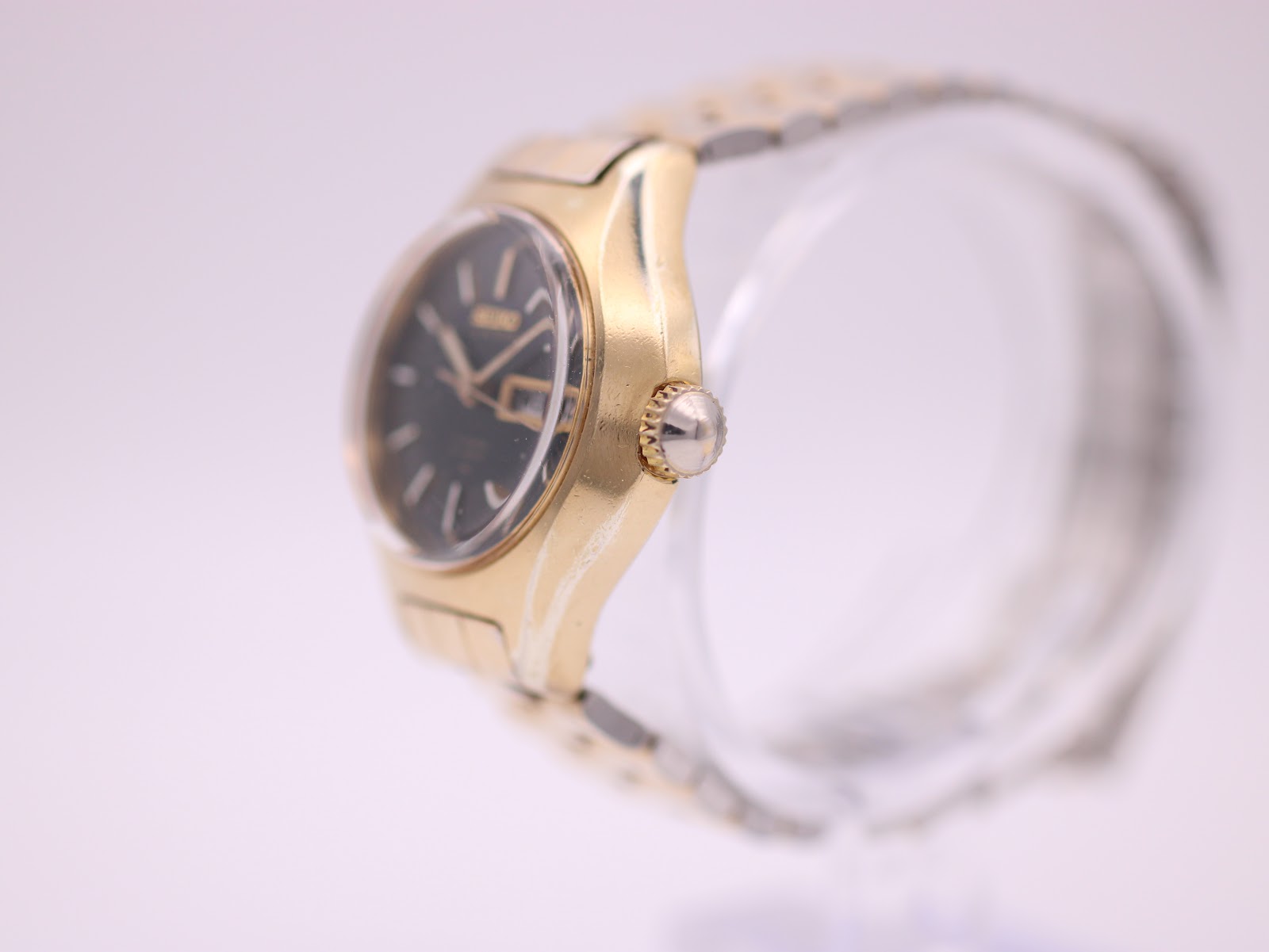 Right side profile of the gold-toned Seiko watch case, showing the crown.