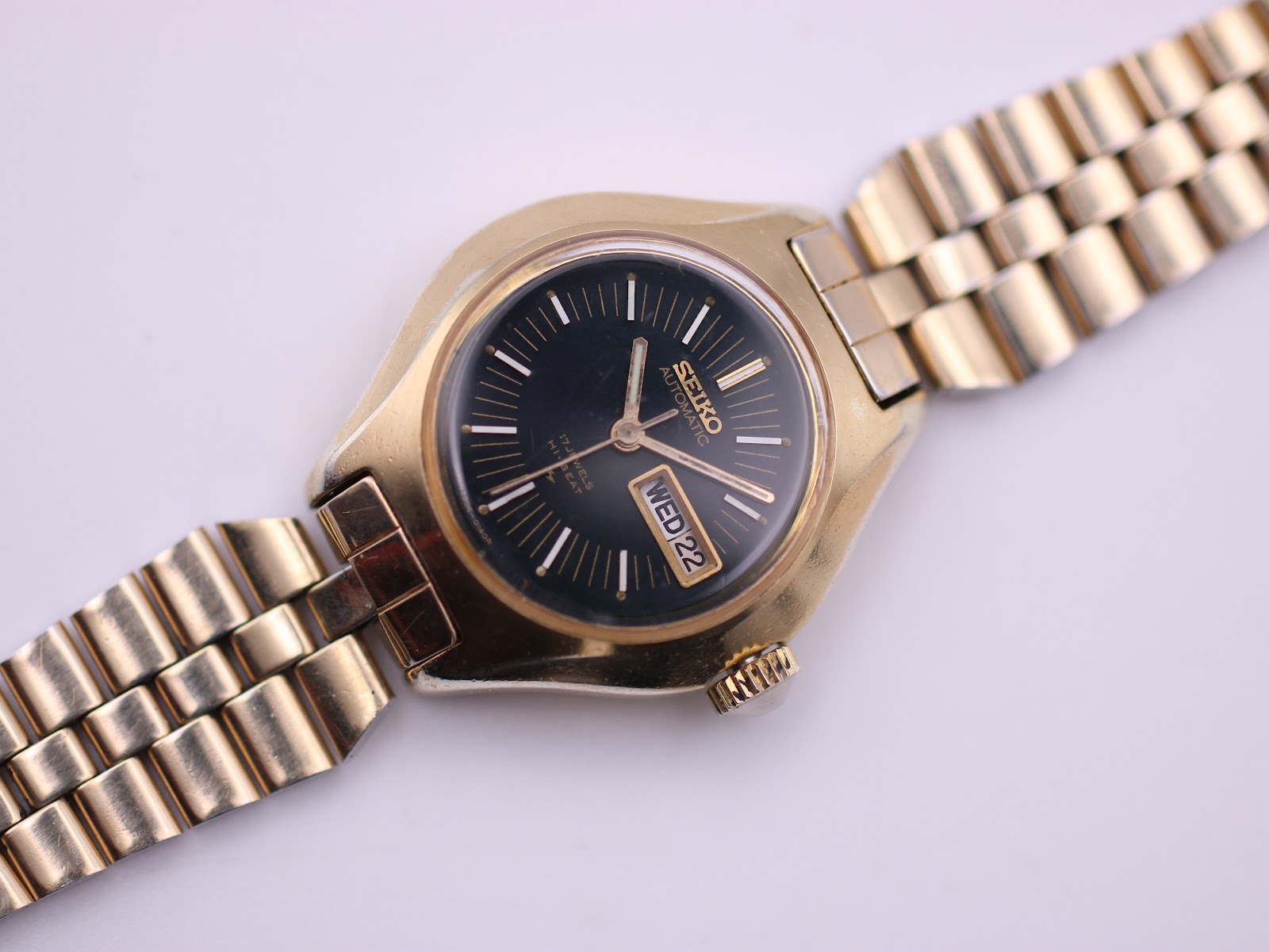 Top-down view of the gold-toned Seiko watch with bracelet extended, highlighting the black dial.
