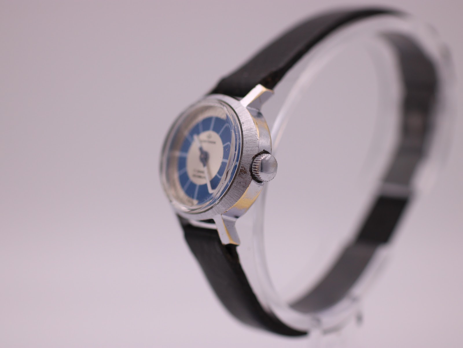 Side profile view of the Craftsman watch on a stand, highlighting the fluted crown and brushed finish of the case.