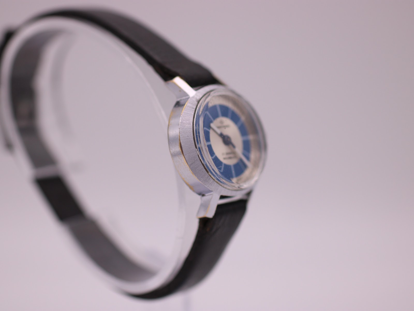 Angled side view of the Craftsman watch, showcasing the small round case and thin black leather strap.