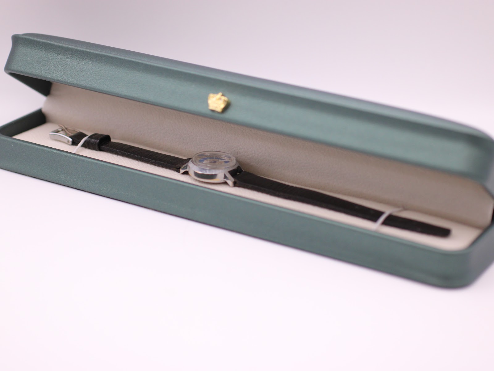 The Craftsman watch and its strap neatly presented inside its original rectangular green watch box.